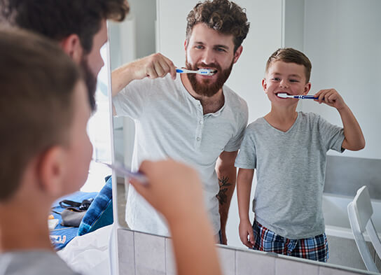 father and son brushing their teeth together