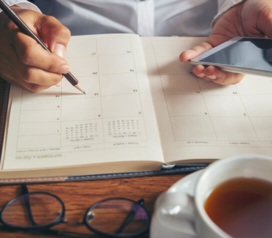 closeup of a person writing in a calendar