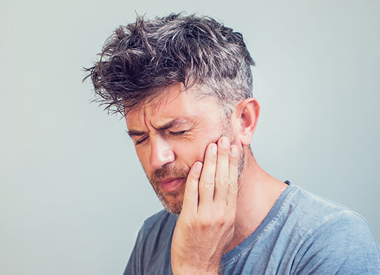 man holding his jaw in pain