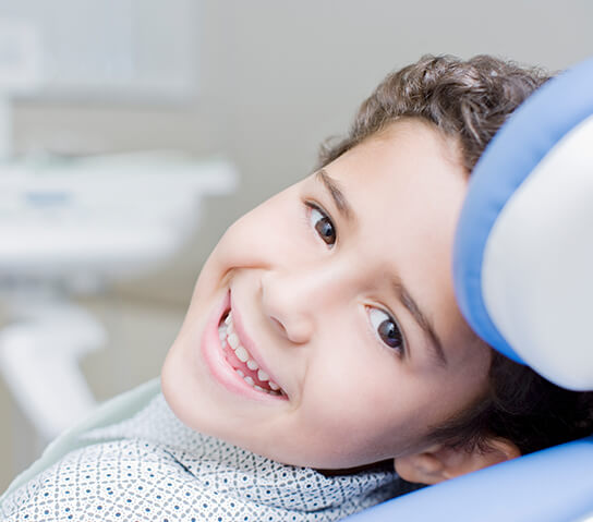 smiling young boy sitting in a dental chair